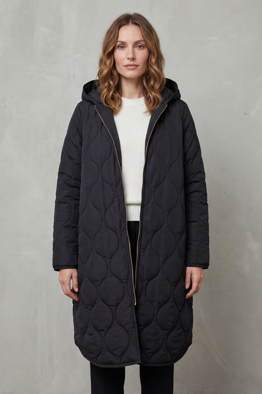 Modella indossa un parka trapuntato lungo con cappuccio, zip frontale e vestibilità rilassata, abbinato a un maglione chiaro._1