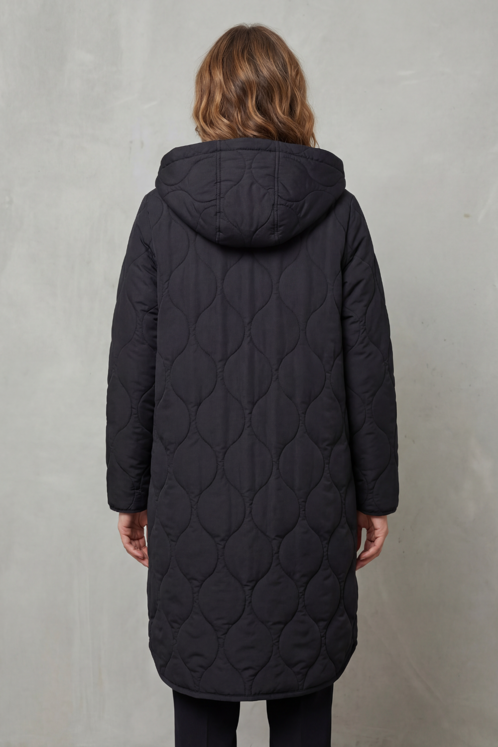 Modella indossa un parka trapuntato lungo con cappuccio, zip frontale e vestibilità rilassata, abbinato a un maglione chiaro._3