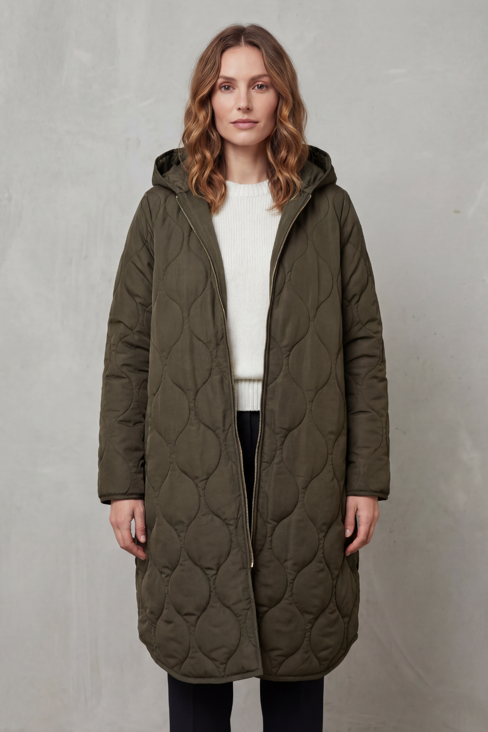 Modella indossa un parka trapuntato lungo con cappuccio, zip frontale e vestibilità rilassata, abbinato a un maglione chiaro._5
