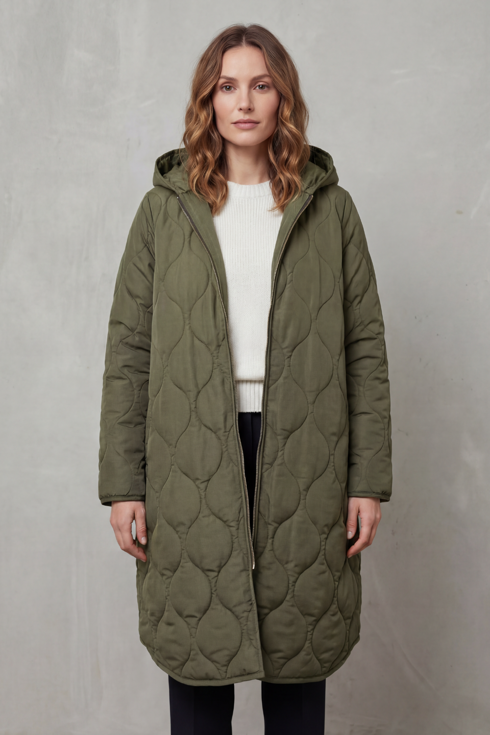 Modella indossa un parka trapuntato lungo con cappuccio, zip frontale e vestibilità rilassata, abbinato a un maglione chiaro._9